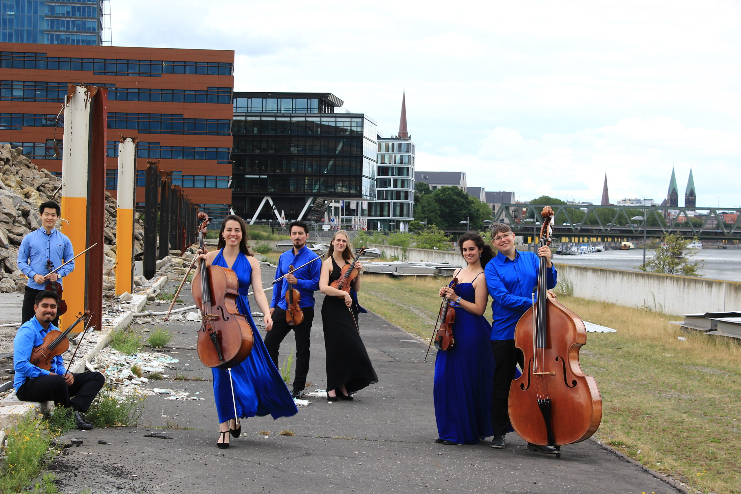 Sieben Musikerinnen und Musiker vom Kammerensemble Konsonanz stheen mit ihren Streichinstrumenten auf einer Baustelle.